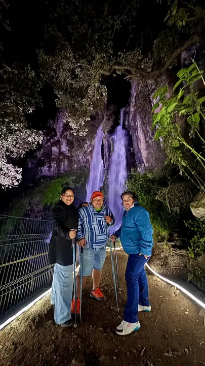 Visitantes frente a la cascada iluminada de Las Brizas