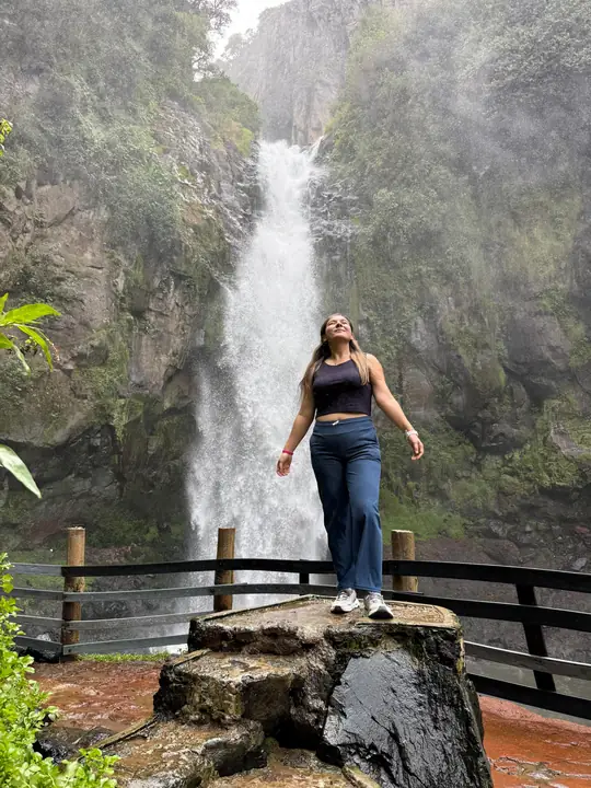 Visitante en un mirador de piedra frente a la cascada